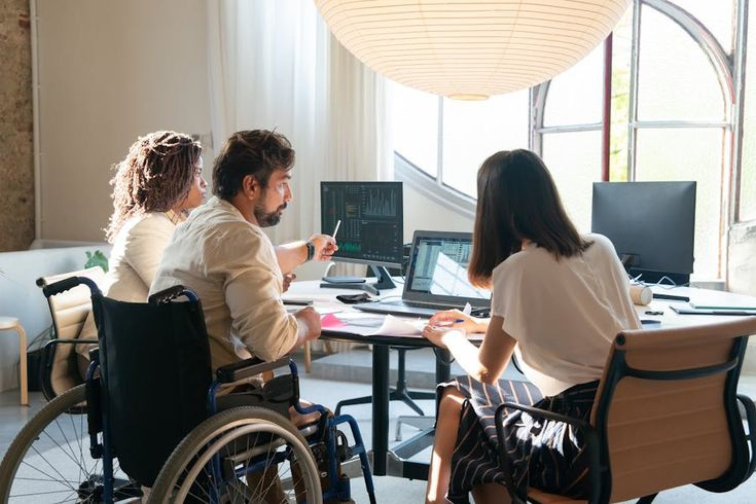 persone in sedia a rotelle attorno a una scrivania di un ufficio